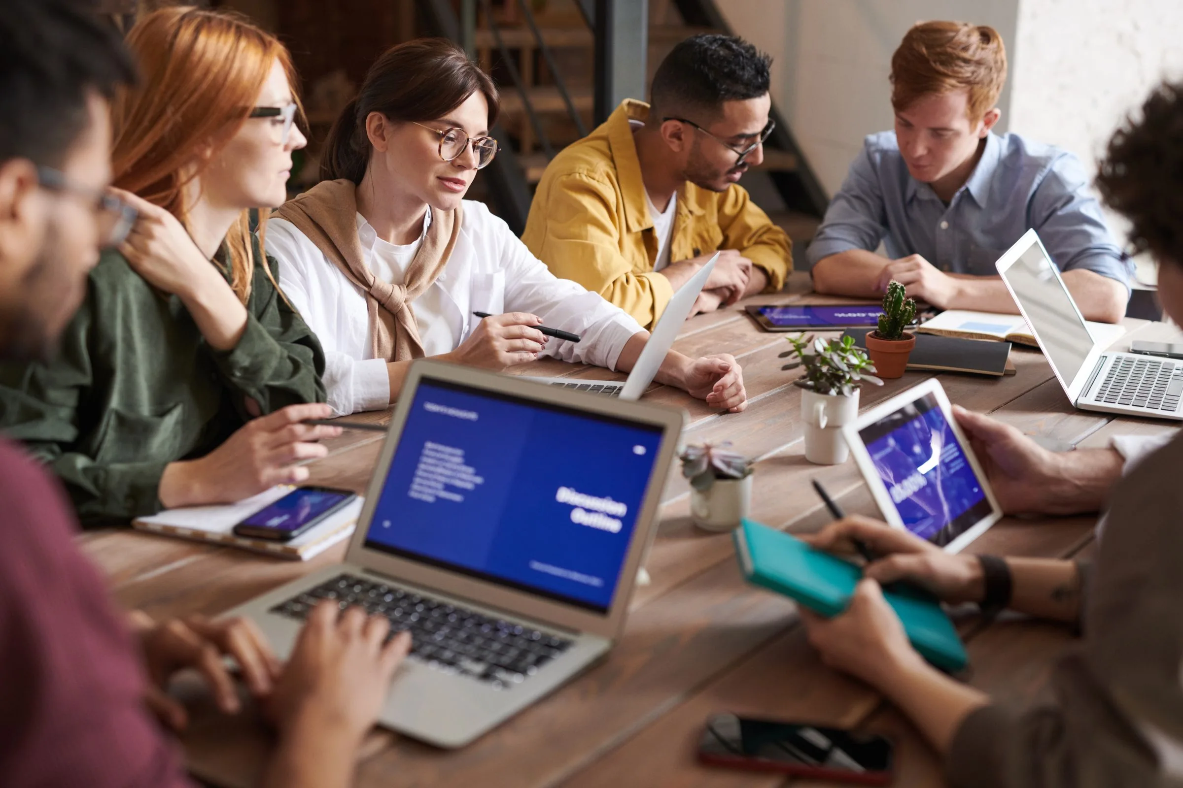 A small team reviewing work together around a wooden table